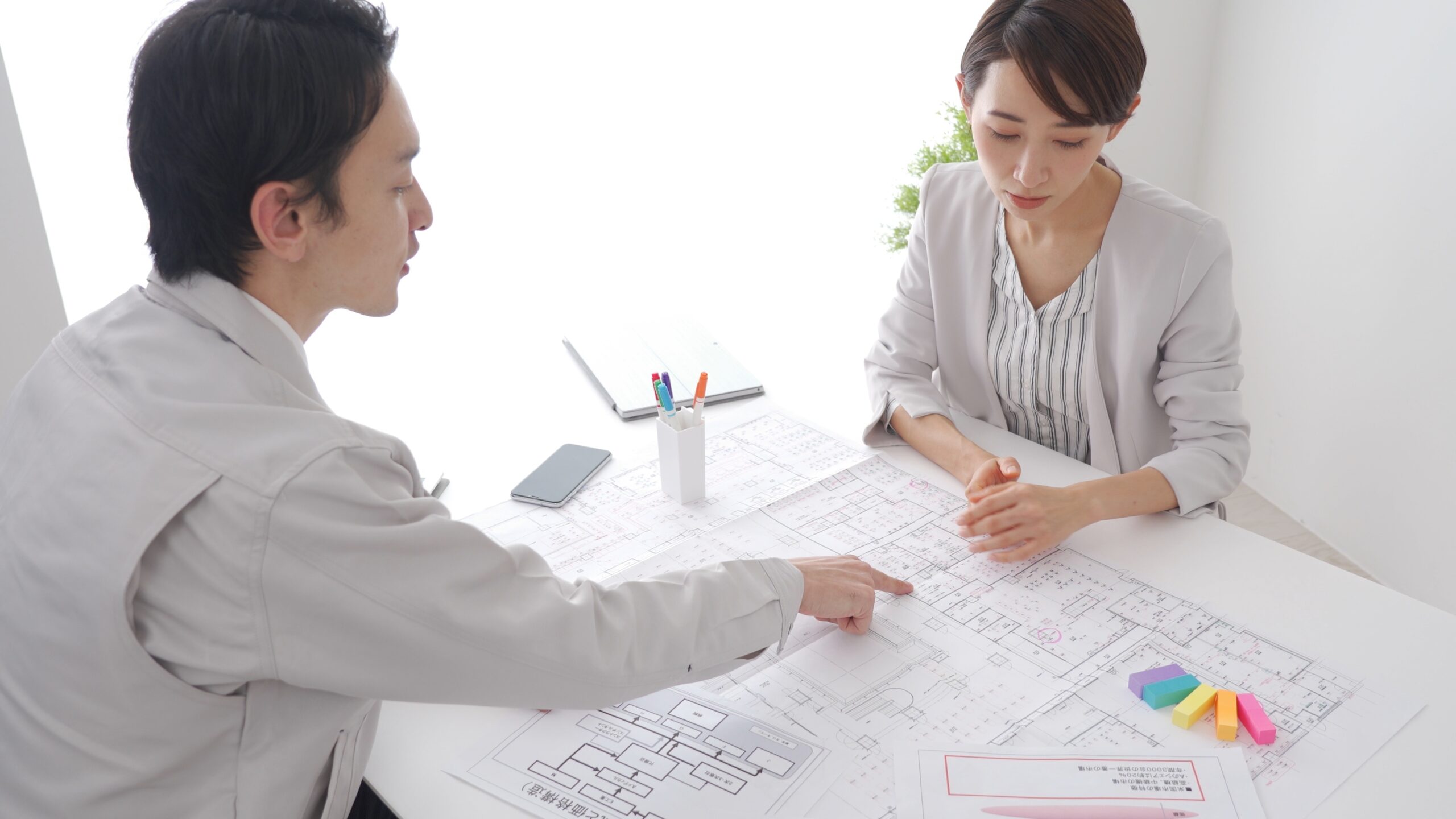 作業着を着た男性とデザイナーの打合せシーン